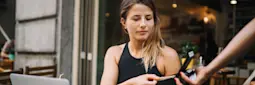 Young woman at a cafe pays for her coffee with card.