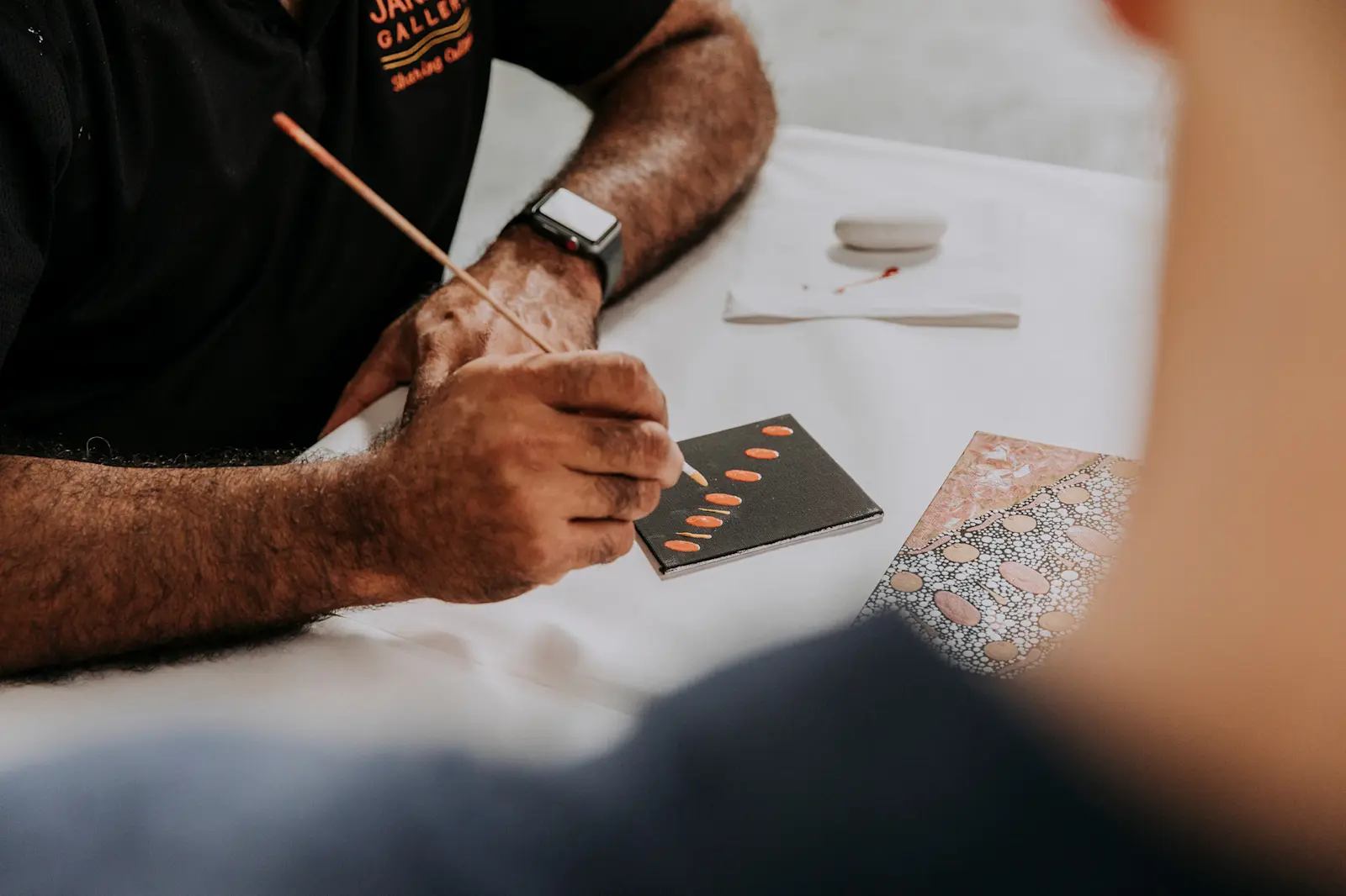 An Aboriginal artist showing guests painting techniques during an Aboriginal art class, QLD © Tourism Australia 