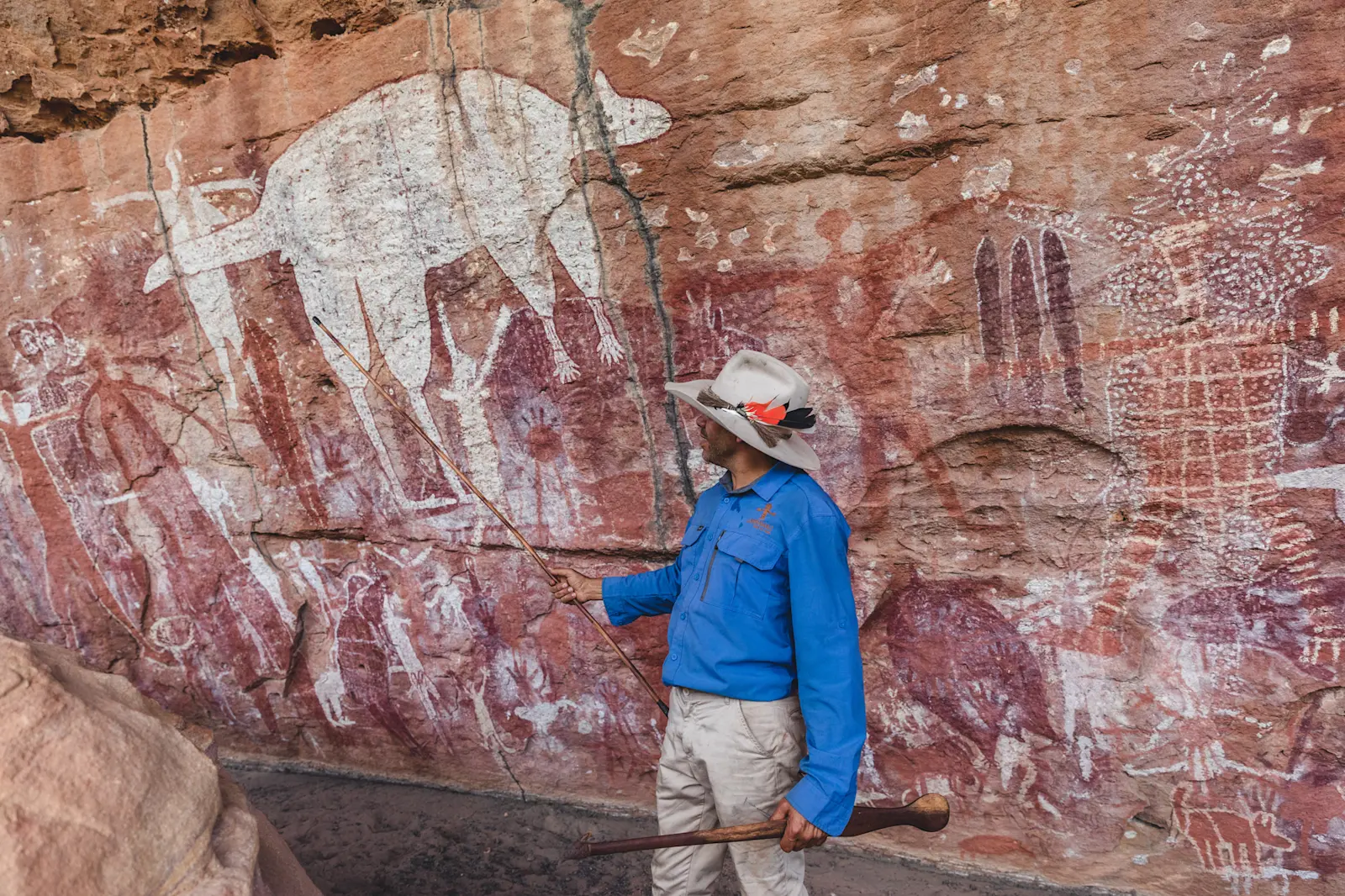 Jarramali Rock Art Tour guide Johnny standing in front of ancient rock art at Magnificent Gallery, QLD © Tourism Tropical North Queensland 