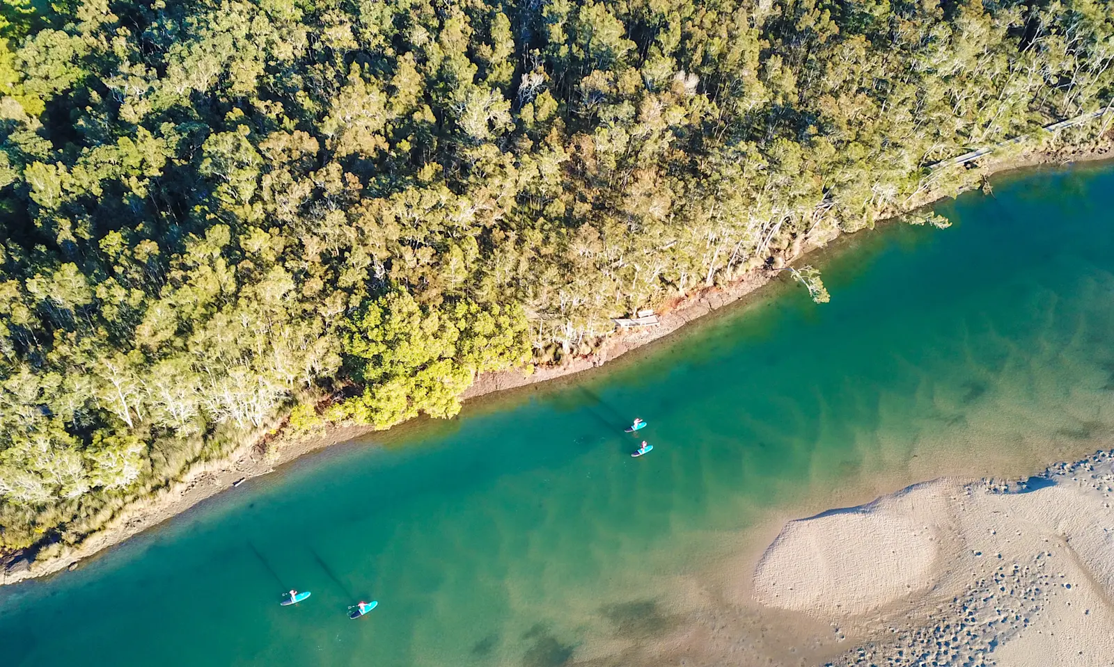 A drone shot of stand-up paddle boarders on a Wajaana Yaam Gumbaynggirr Adventure Tours experience on the Corindi River, NSW © Destination NSW
