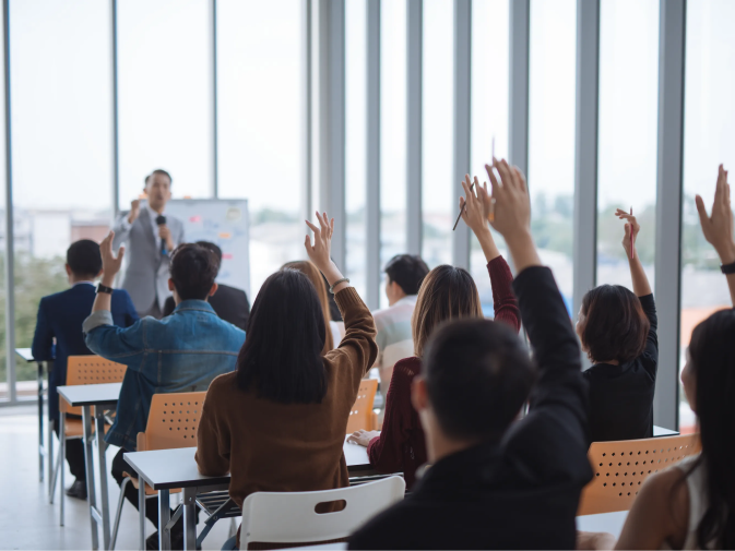 Group of students raising their hands to answer the instructor's question