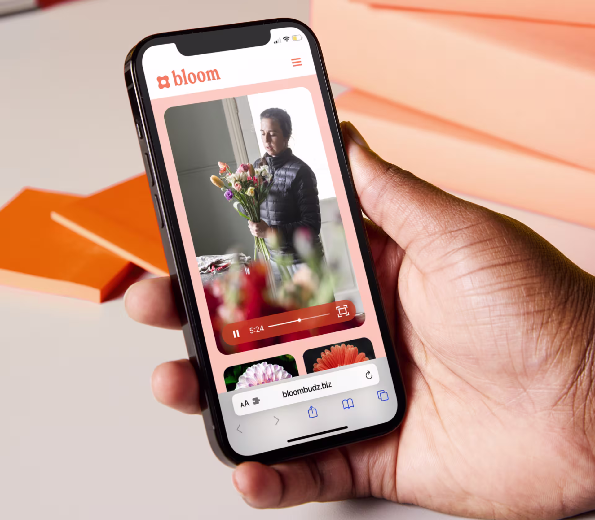 Image of a hand holding a phone with the screen showing a video player embedded on a mobile webpage