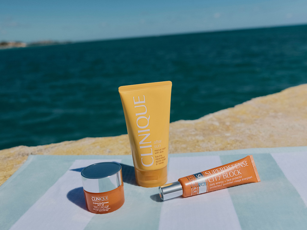 A selection of Clinique skincare products on a beach